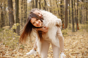 Mother and her daughter playing and having fun in autumn forest