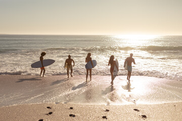 Wall Mural - Multi-ethnic group of male and female, surfing on the beach