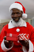 Portrait Of Senior African American Man Wearing A Costume Of Santa Claus And Holding Gifts