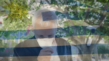Poster - Animation of flag of uruguay waving over caucasian man wearing face mask in city street
