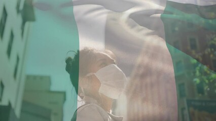 Poster - Animation of flag of nigeria waving over african american woman wearing face mask in city street