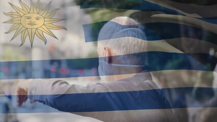 Poster - Animation of flag of uruguay waving over caucasian man wearing face mask in city street