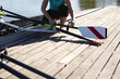 © Wavebreak Media - Low section of senior caucasian female rower attaching oars to the boat near the wooden dock