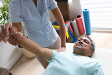 Mixed Race Female Physiotherapist Helping Senior Man Stretching His Arm