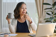 © saltdium - Coffee break with senior old businesswoman while eating a doughnut, online working work at home office.