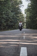 © perfectlab - A young happy couple rides a motorcycle on an asphalt road in the forest, freedom and speed