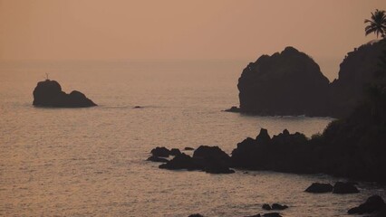 Wall Mural - Wide angle shot of Arabian sea during the sunset with rocky formations between the sea water as seen from the Cabo De Rama at Goa in India. Natural sea sunset background. Rocky formations in sea water