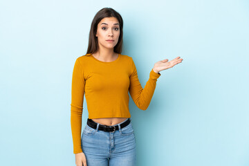 Poster - Young caucasian woman isolated on blue background making doubts gesture