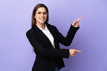 Wall Mural - Business woman isolated on purple background pointing finger to the side and presenting a product