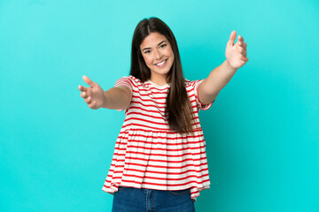 Wall Mural - Young Brazilian woman isolated on blue background presenting and inviting to come with hand