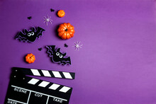 Movie Clapper Board With Halloween Decorations On A Purple Background With Copy Space.