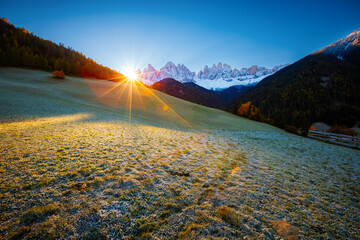 Autocollant - The sun's rays break through the peaks of the Odle Ridge in St. Magdalena village. Dolomite alps, Italy, Europe.