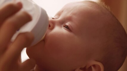 footage of baby lying on mothers hand and drinking milk from bottle. caucasian loving mother feeding