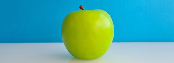 Green beautiful ripe apple on blue background