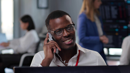 Smiling African American consultant talking to client on phone working in call center