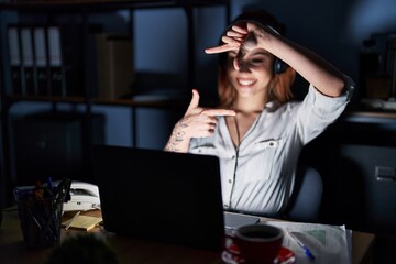 Poster - Young caucasian woman working at the office at night smiling making frame with hands and fingers with happy face. creativity and photography concept.