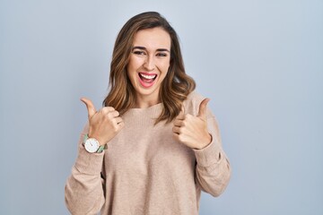 Poster - Young woman standing over isolated background success sign doing positive gesture with hand, thumbs up smiling and happy. cheerful expression and winner gesture.