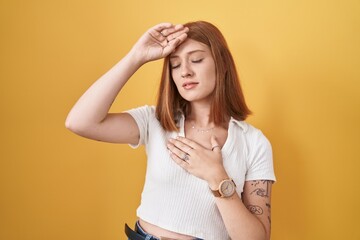 Wall Mural - Young redhead woman standing over yellow background touching forehead for illness and fever, flu and cold, virus sick