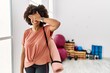 African american woman with afro hair holding yoga mat at pilates room smiling and laughing with hand on face covering eyes for surprise. blind concept.