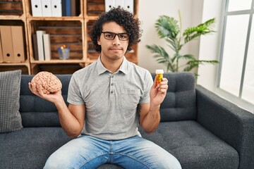 Wall Mural - Hispanic man with curly hair working on depression holding pills skeptic and nervous, frowning upset because of problem. negative person.