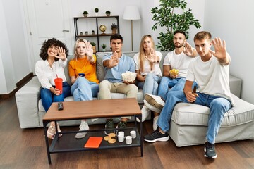 Sticker - Group of people eating snack sitting on the sofa at home with open hand doing stop sign with serious and confident expression, defense gesture