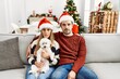 © Krakenimages.com - Young couple of wife and husband sitting on the sofa wearing christmas hat at home thinking attitude and sober expression looking self confident