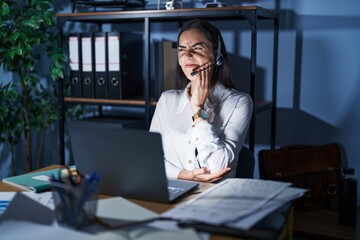 Sticker - Young brunette woman wearing call center agent headset working late at night touching mouth with hand with painful expression because of toothache or dental illness on teeth. dentist