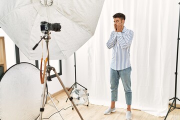 Canvas Print - Arab young man posing as model at photography studio tired hands covering face, depression and sadness, upset and irritated for problem