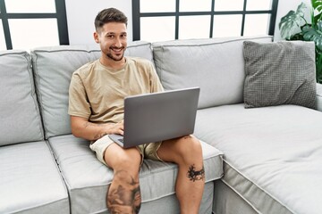 Wall Mural - Young hispanic man smiling confident using laptop at home