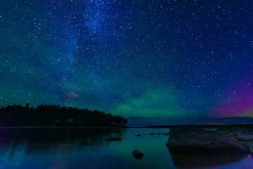 Wall Mural - night landscape with a starry sky and the milky way with stars and constellations over the water of 