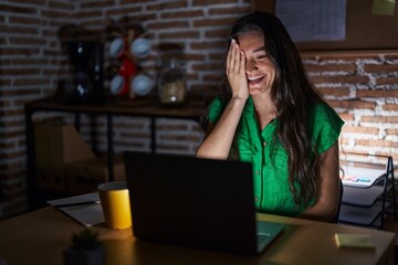 Sticker - Young teenager girl working at the office at night covering one eye with hand, confident smile on face and surprise emotion.