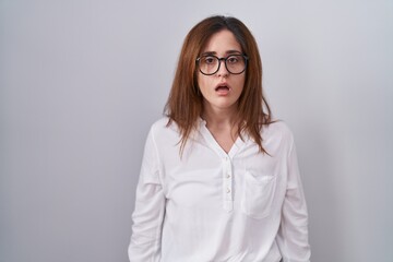 Sticker - Brunette woman standing over white isolated background afraid and shocked with surprise and amazed expression, fear and excited face.