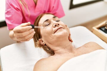 Poster - Middle age caucasian woman having facial treatment at beauty center