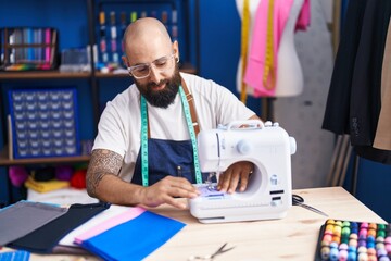 Poster - Young bald man tailor smiling confident using sewing machine at clothing factory