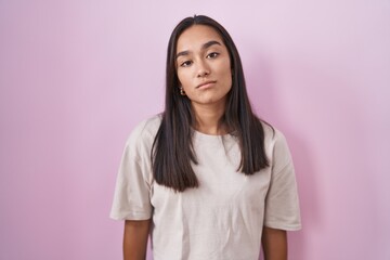 Canvas Print - Young hispanic woman standing over pink background looking sleepy and tired, exhausted for fatigue and hangover, lazy eyes in the morning.