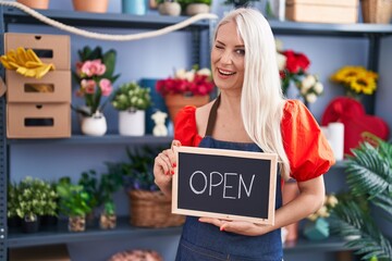 Sticker - Caucasian woman working at florist holding open sign winking looking at the camera with sexy expression, cheerful and happy face.