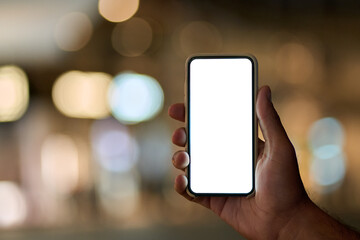 Male hand holding smartphone with white mock up screen on night city lights background. Man showing blank mobile display mockup template of cell phone with empty space for apps advertising concept