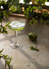 Wall Mural - Beautiful green coctail with mint syrup,lime and green leaves on stone background.Close up of elegant drink in crystal glass.