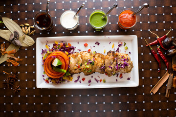 Murgh Makhmali Tikka or chicken malai tikka boti kabab with raita, mint, sauce, chutney and ketchup served in a dish isolated on table background top view of bangladesh food