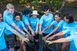 Team of young and diversity volunteer worker group enjoy charitable social work outdoor in mangrove planting project wearing blue t-shirt while joining hand in assemble unity