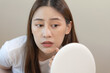 © Pormezz - skin problem treatment. Women looking acne on her face in the mirror.