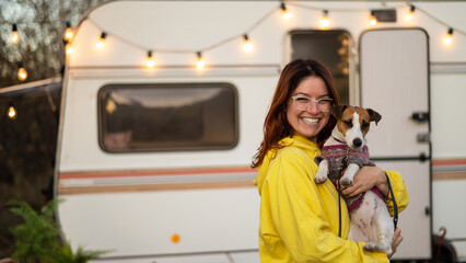 red-haired caucasian woman hugs a dog and lives in a motor home. travel by trailer.