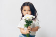 © Tatiana - portrait of a cute, pleasant little girl with a bouquet of daisies in her hands smelling flowers, standing in a white T-shirt on a light background