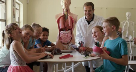 Male teacher and group of kids smiling in human anatomy class