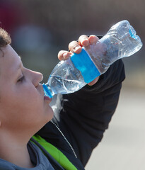  The boy drinks water from a plastic bottle.