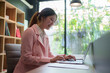 © amnaj - Beautiful Asian businesswoman working on a desk with a laptop with a smiling face while looking at the document received in the office.