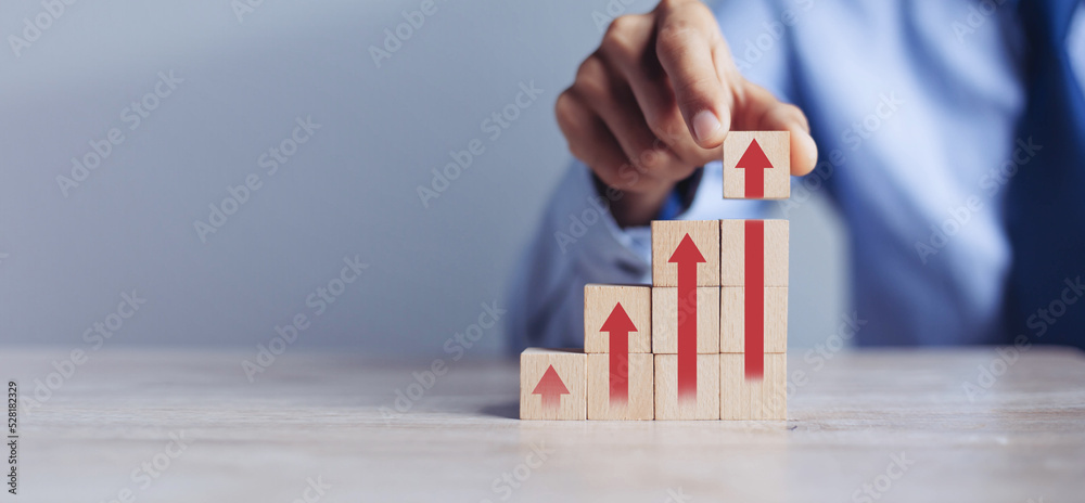 businessman hand arranging wood block stacking as step stair with arrow ...