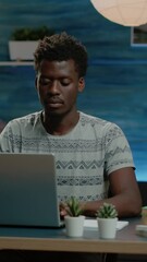 Poster - Vertical video: Entrepreneur using laptop for remote online work. Corporate worker typing on keyboard, working from home on device. Man smiling and looking at camera while doing business project