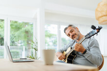Smiling Bearded Musician Mature Adult Man Playing Acoustic Guitar, Using Laptop