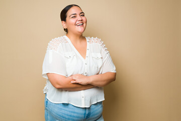 cheerful fat latin woman smiling against a pastel yellow background